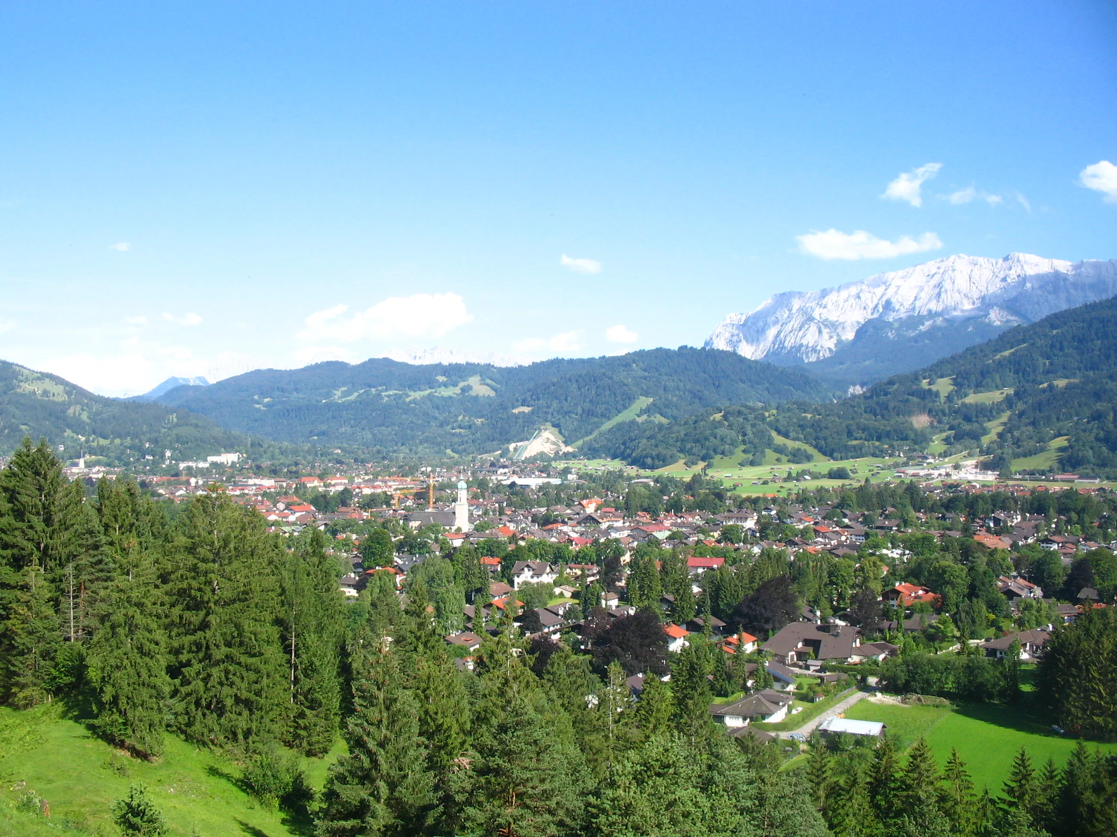 A Bavarian alpine town below mountains and blue sky.