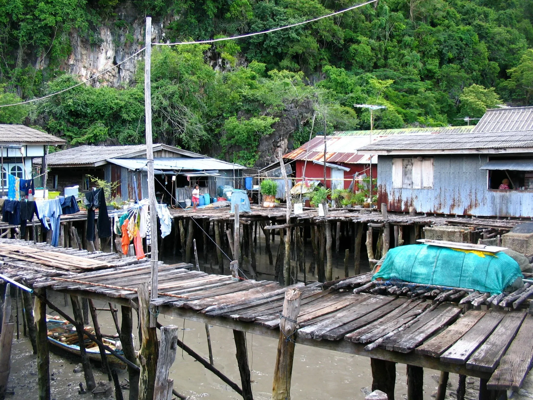 A village on wooden stilts against dense green hillside.